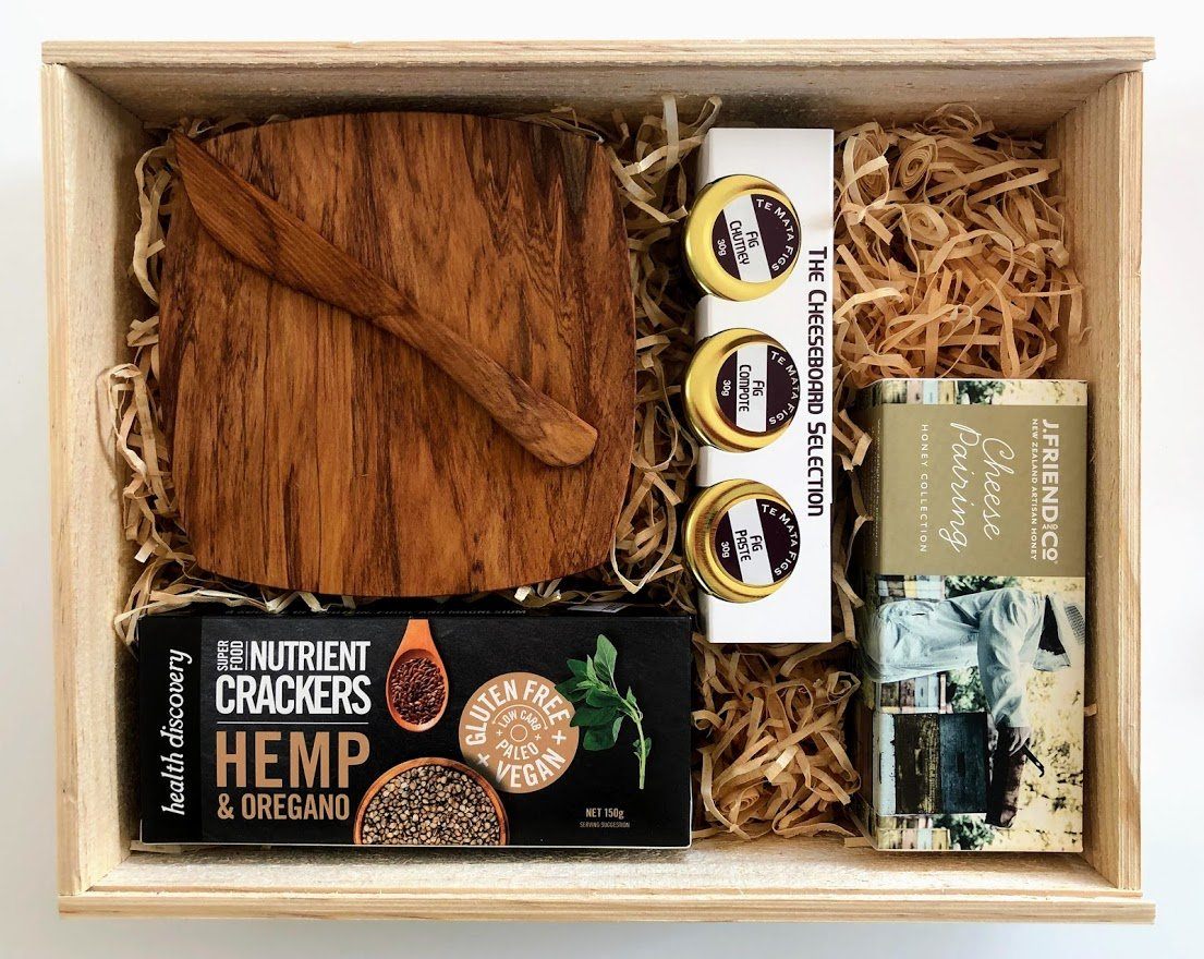 Boxsmith gift box featuring the Cheeseboard gift box. Includes NZ Native Rimu wood cheeseboard and wood knife, Bonnie Oatcakes, J Friend Cheese pairing honey and Te Mata Fig collection. Easy delivery NZ wide