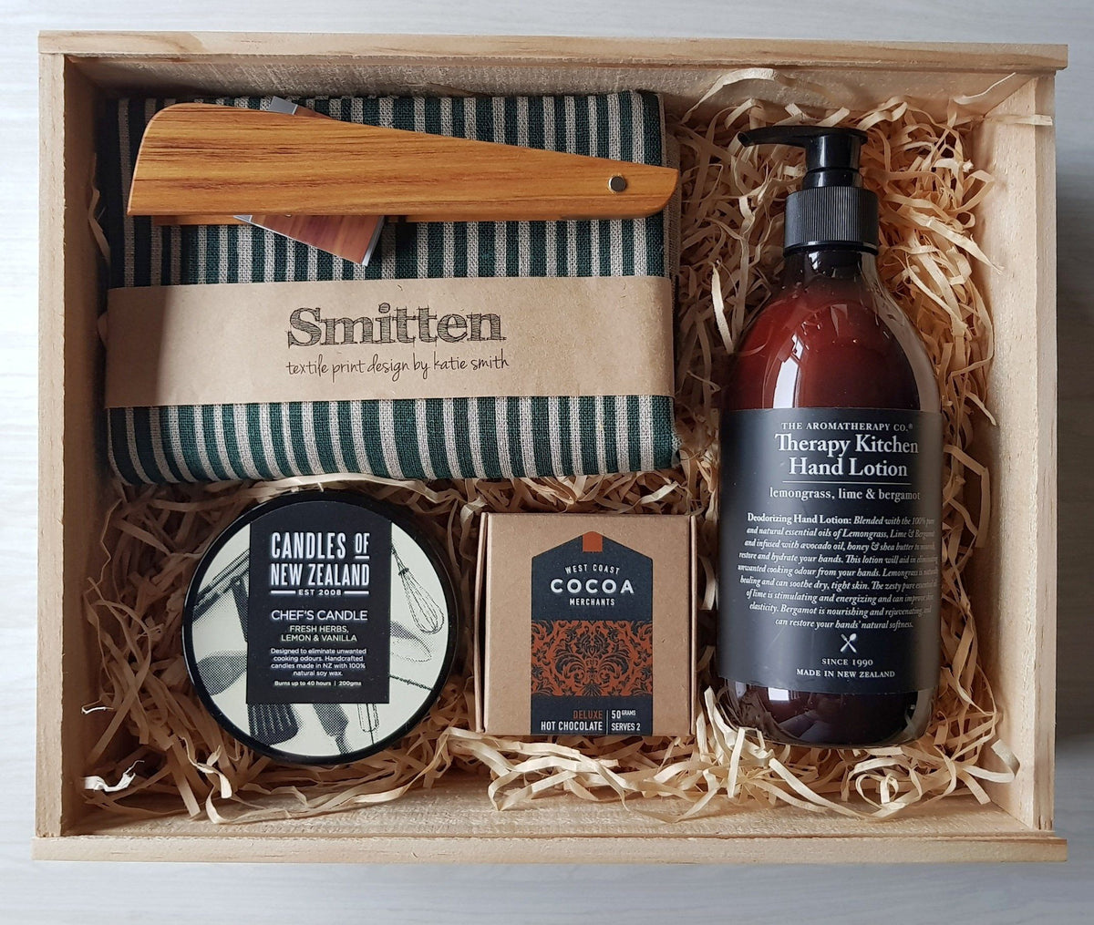 Boxsmith gift box with Smitten Tea towel, MZ design tongs, Aromatherapy Co hand lotion, chef candle, west coast cocoa. Easy delivery NZ wide of our NZ online gifts. NZ Gift Hamper & Gift basket alternative.